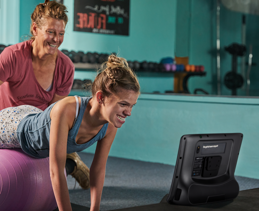 Femme utilisant son appareil de technologie d'assistance Tobii Dynavox TD I-Series à la salle de sport